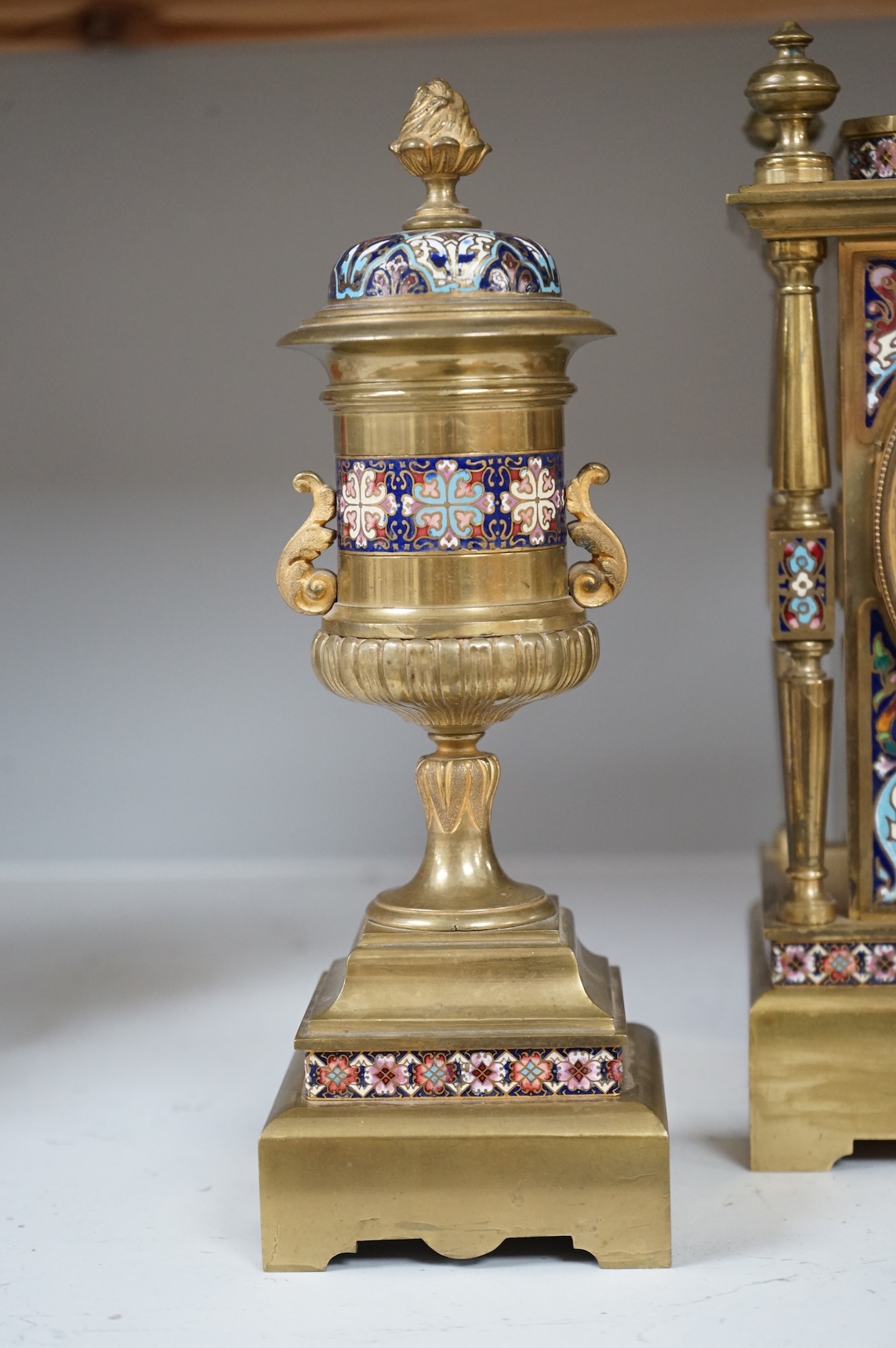 A large early 20th century French brass and champlevé enamel clock garniture, 35cm high